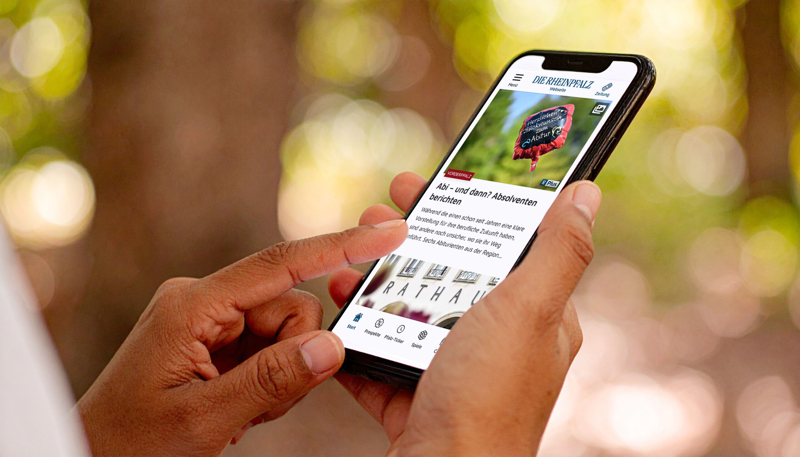 Person h&auml;lt Smartphone mit der RHEINPFALZ-App &ndash; aktuelle Artikel&uuml;bersicht ge&ouml;ffnet.